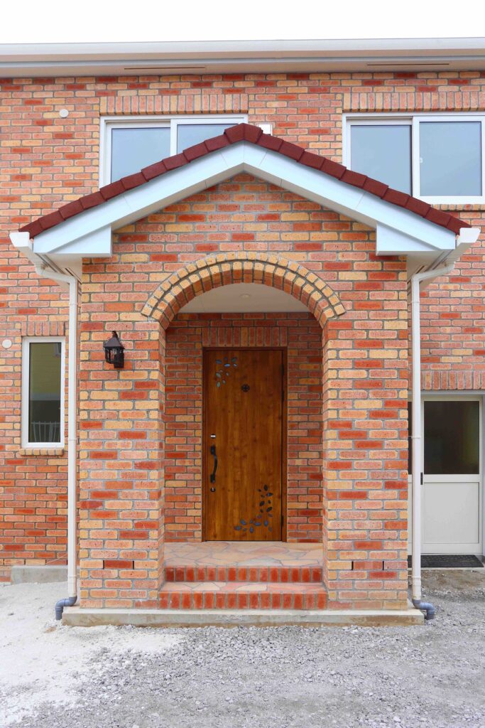 中世のお城のような優美なレンガ積みの家の３つのアーチからなる玄関ポーチ